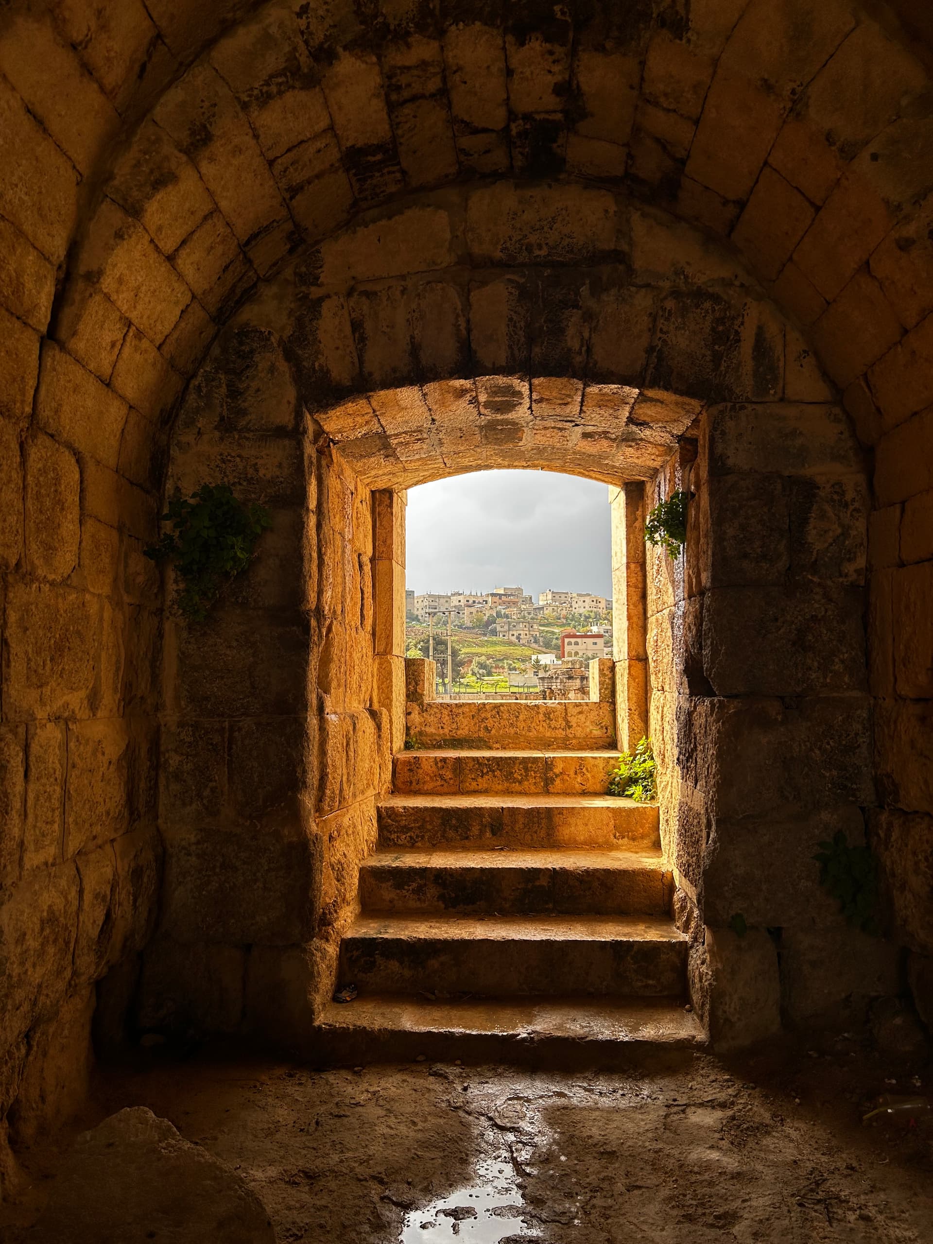 A stone archway opening onto the landscape — the way letters frame what comes through them